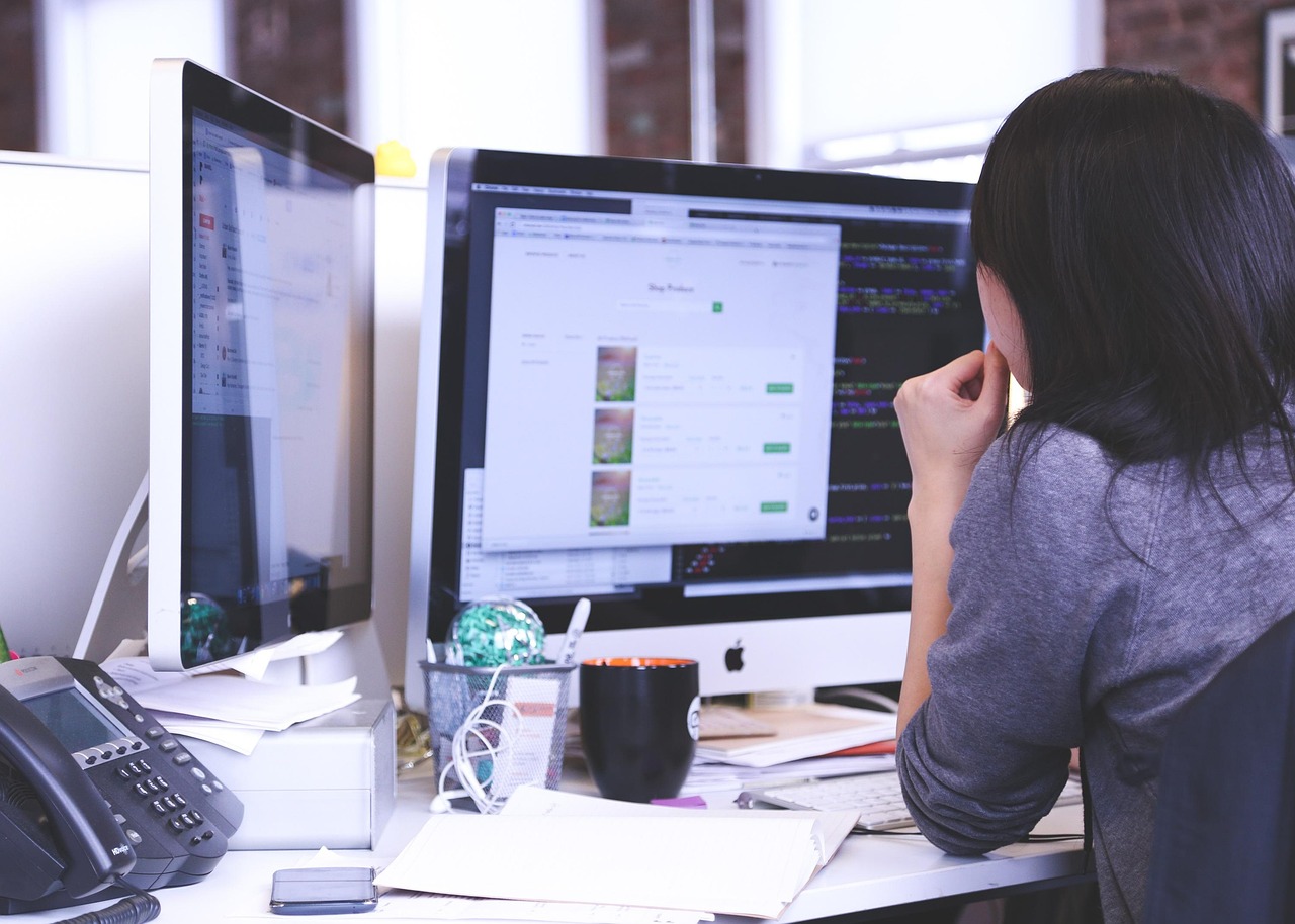 A woman at a desk reviewing a web page on a large monitor